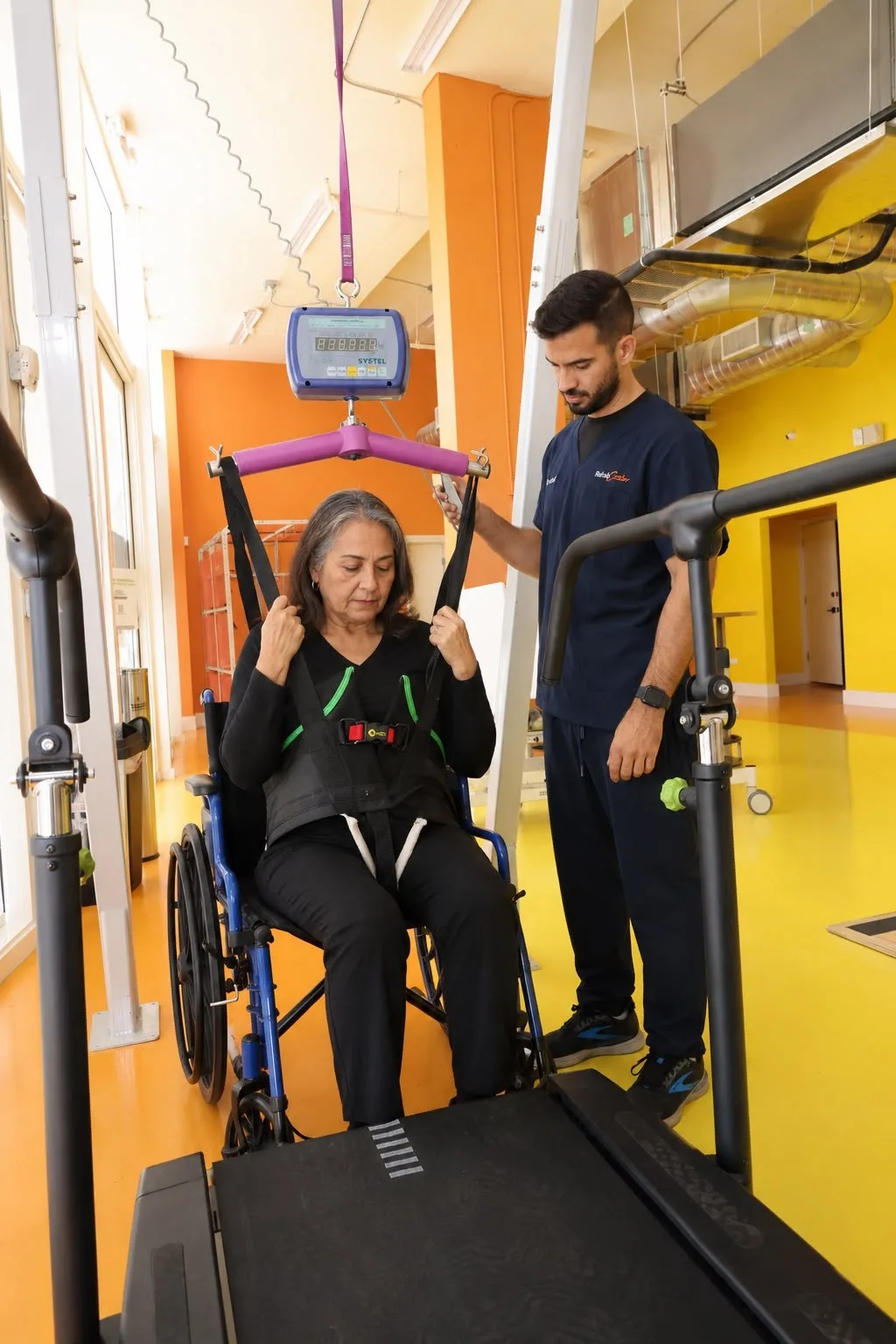 Therapist assisting a patient during body-weight-supported walking practice at RehabCenter